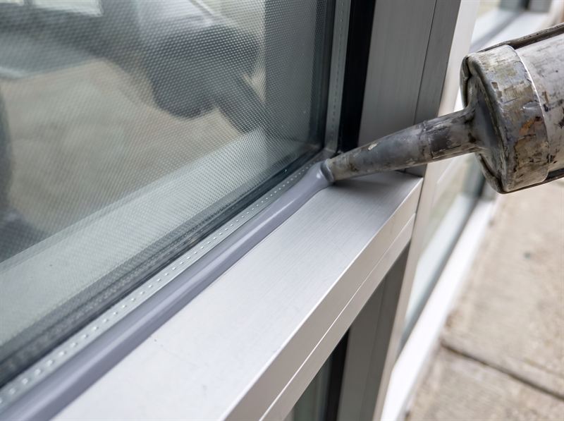 Gray structural silicone anchoring security film to an aluminium storefront frame